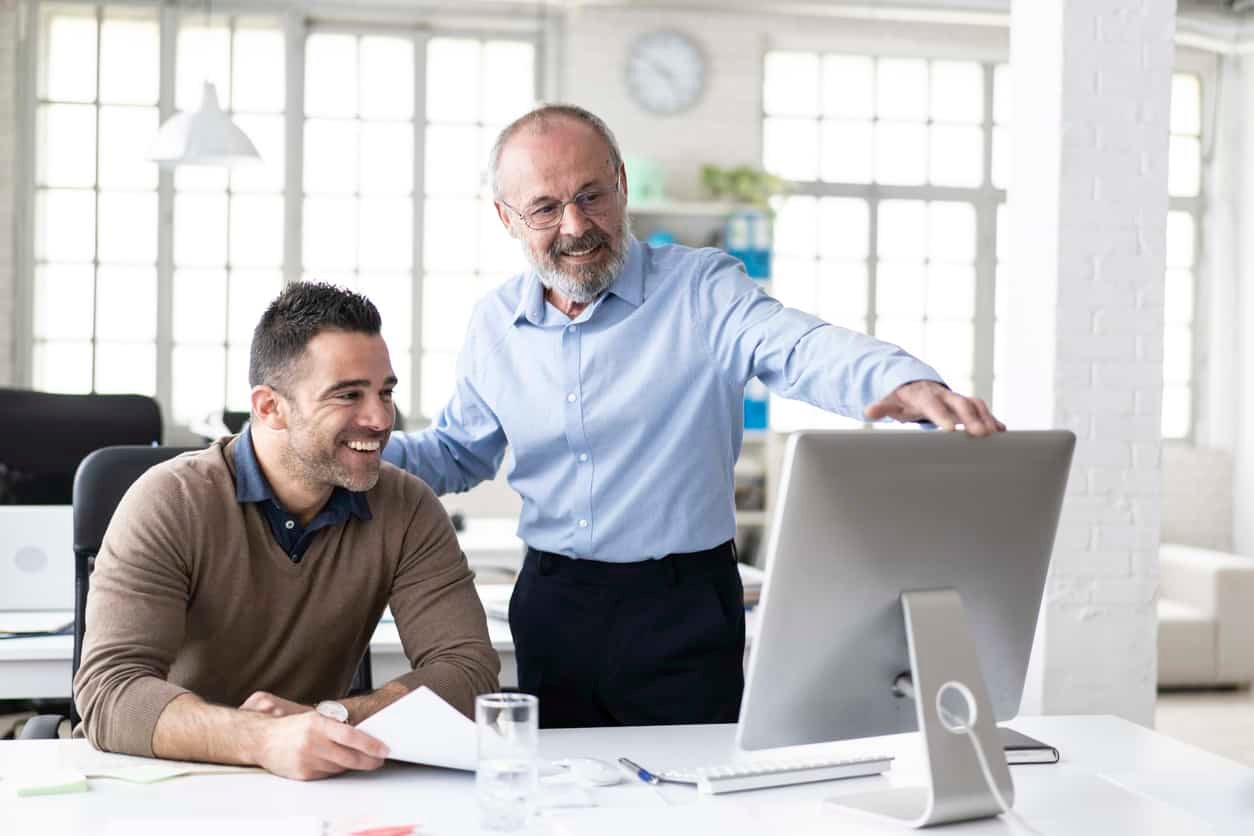 Senior manager explaining to coworker something on computer